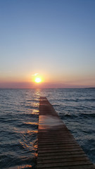 Obraz premium Bridge into the sea at sunset. sunset pier with clouds in the sea.