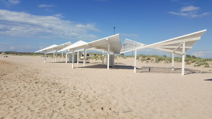 Early morning on a sandy beach without people. Sun loungers for sunbathing on the sea beach. sun loungers, summer, sunshade, beach, deck chairs