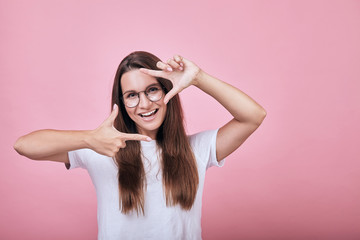 Cool happy smiling girl shows frame borders for photo with her hands