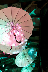 Colorful umbrellas hanging under the ceiling light up with bright stars.