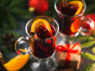 Christmas mulled wine of red wine with cinnamon, orange, cranberries on the festive table with spruce branches