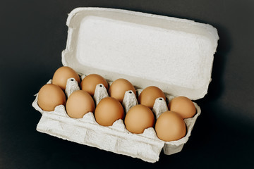 chicken eggs in a paper gray crate on a black background