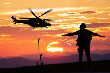 Silhouette of helicopter, soldiers rescue helicopter operations on sunset sky background.