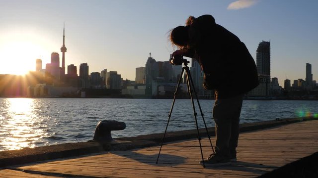 Photographer with tripod and dslr taking photos of Toronto cityscape sunset 1