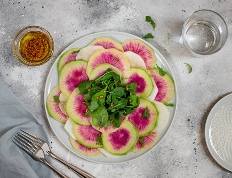 detox salad of watermelon radish and arugula in a plate. Home made healthy food. light concrete or stone background. top view