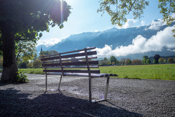 Empty metal bench in public park at Interlaken with mountain and clear blue sky background , copy space