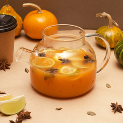 Pumpkin tea in a glass teapot with a lemon on background.-Image