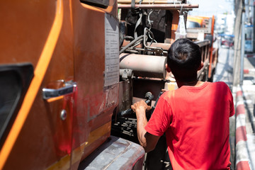 Back view of truck crane driver wearing red t-shirt is controlling crane working on electric power poles.