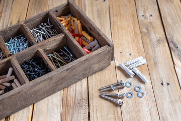 Different types and sizes of screw in wooden organizer box, work tools. - obrazy, fototapety, plakaty