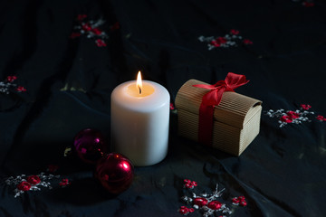Lit candle and gift box with red ribbon