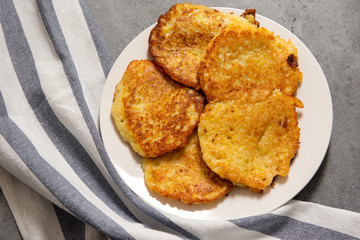 1 white plate with potato pancakes on a gray background, towel,