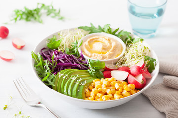 vegan avocado sweet corn lunch bowl with hummus, red cabbage, radish and sprouts
