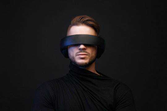 Portrait of model young man with beard in glasses of virtual reality on dark background. Augmented reality, future technology concept. VR. Free space for text.