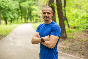 Sporty man with crossed hands dressed in blue t-shirt