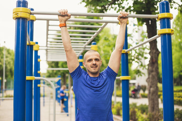 Obraz premium Man doing pull up workout in the park