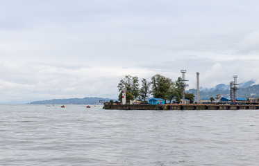 Cargo port with a lighthouse on a rainy day on the Black Sea embankment of Batumi city - the capital of Adjara in Georgia