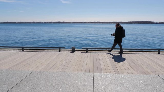 Photographer walking along waterfront boardwalk taking photos 3