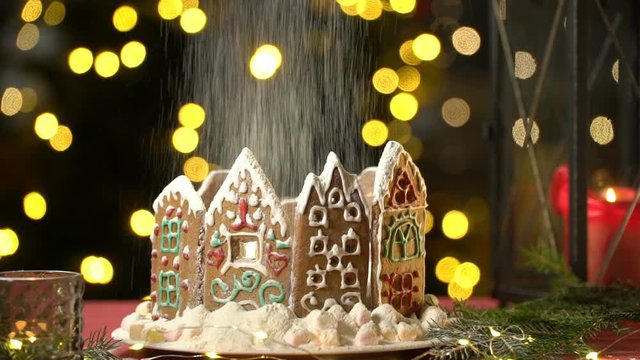 Icing sugar falling on a Christmas gingerbread house like snowfall. The concept of preparation for the Christmas holidays