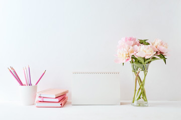 Mockup with a blank desk calendar and pink peonies in a vase on a white background