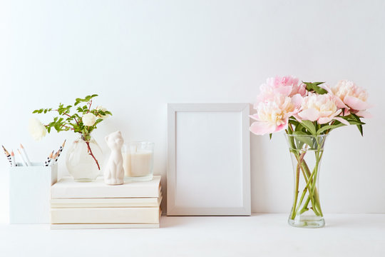 Home interior with decor elements. White frame, pink peonies in a vase, interior decoration