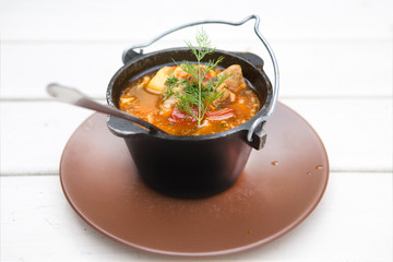 cauldron with soup isolated on a light wooden background