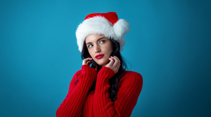 Young woman with Santa hat thoughtful pose on a dark blue background