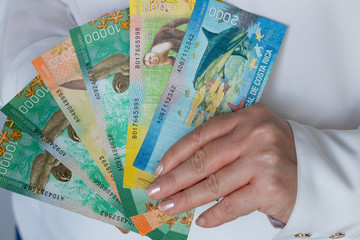 woman holds Costa Rican money, Colones, various banknotes in her hand