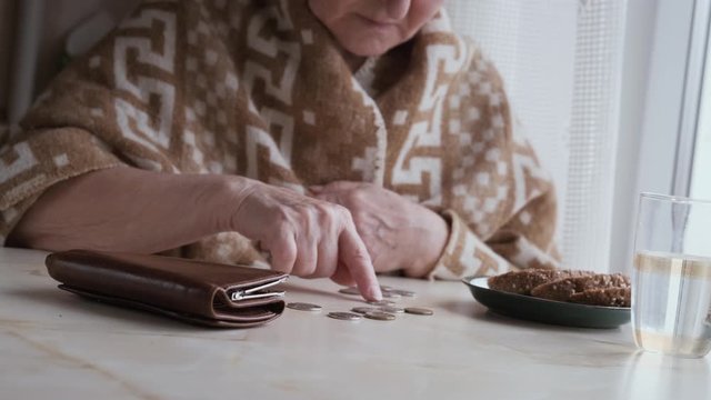 Poor old woman counting coins sitting at home with tolom, closeup