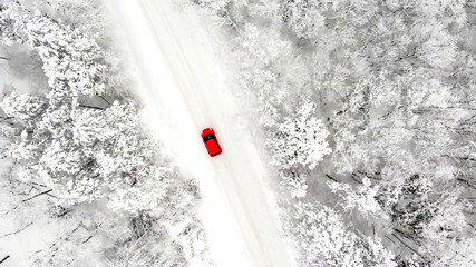 red car driving on an iced snow road, drone aerial view