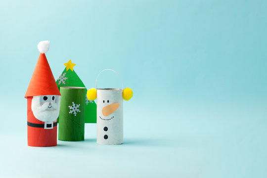 Paper toy Santa, Snowman, tree for Xmas party. Easy crafts for kids on yellow background, copy space, die creative idea from toilet tube roll, recycle reuse eco concept