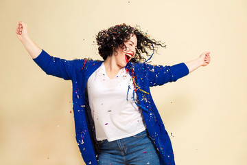 Young laughing woman in confetti celebrates. Yellow background. - Powered by Adobe