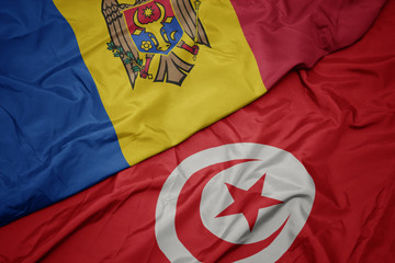 waving colorful flag of tunisia and national flag of moldova.