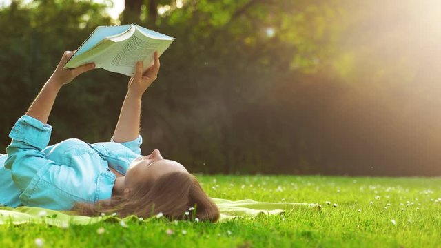 Woman lies on the grass and reads a book.