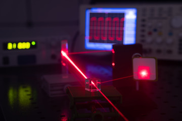 Experiment in optic lab with laser device. Red laser on optical table in physics laboratory