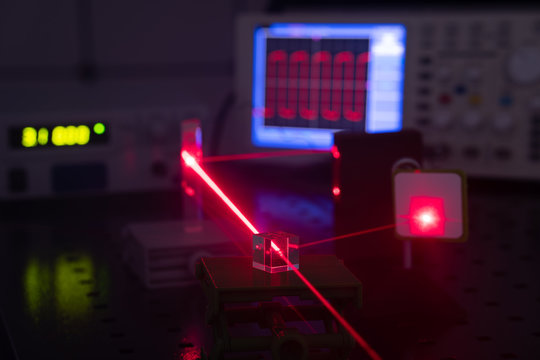 Experiment in optic lab with laser device. Red laser on optical table in physics laboratory