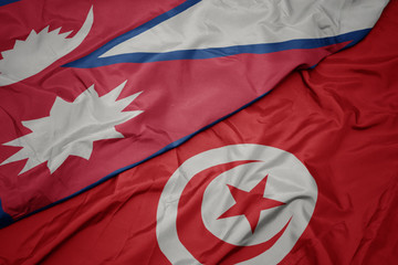 waving colorful flag of tunisia and national flag of nepal.