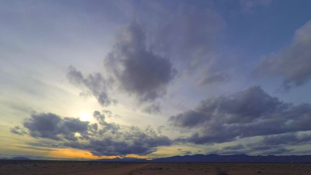 Blue and orange cloudy sunrise time lapse in empty desert landscape