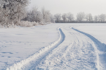 Fototapeta na wymiar Tracks in snow of cars along the field. Close-up.