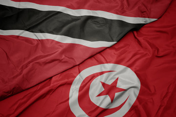 waving colorful flag of tunisia and national flag of trinidad and tobago.