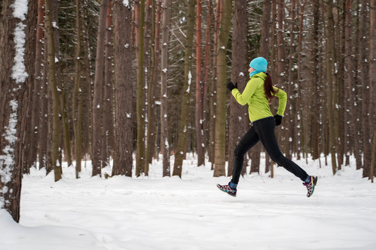 Image of young sportswoman running in winter forest