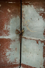 Rusty and stained old brass door with a padlock