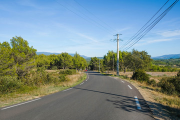 Deserted country road in Provence on a sunny day. Mountains on the horizon.