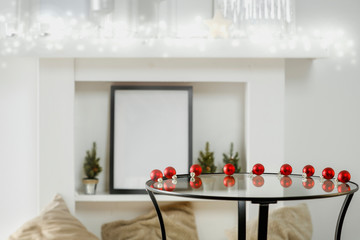 Round glass table with some winter ornaments and decoration with bright white fireplace wall background. Christmas time. Nice luxurious home interior.