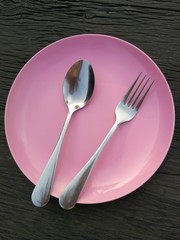 fork and spoon on pink plate