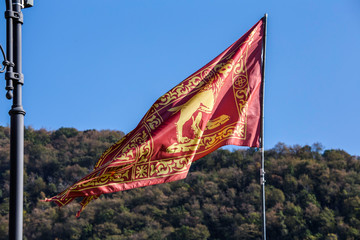 Venice red flag with golden lion waving in the blue sky background.