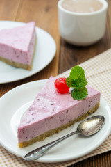 Cheesecake slice with berries and coffee cup, pink cheesecake on wooden background, dessert or breakfast. Sweet food.