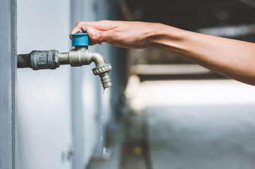 hand woman opening faucet or water tap and close for save water energy protect shortage. environment day concept. © thithawat