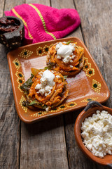 Mexican chicken tinga sopes with chipotle pepper and fresh cheese  on wooden background