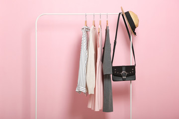 fashionable clothes on hangers on a wardrobe rack on a colored background. - obrazy, fototapety, plakaty