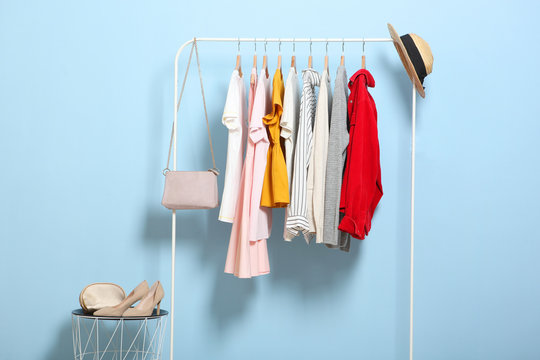 fashionable clothes on hangers on a wardrobe rack on a colored background.